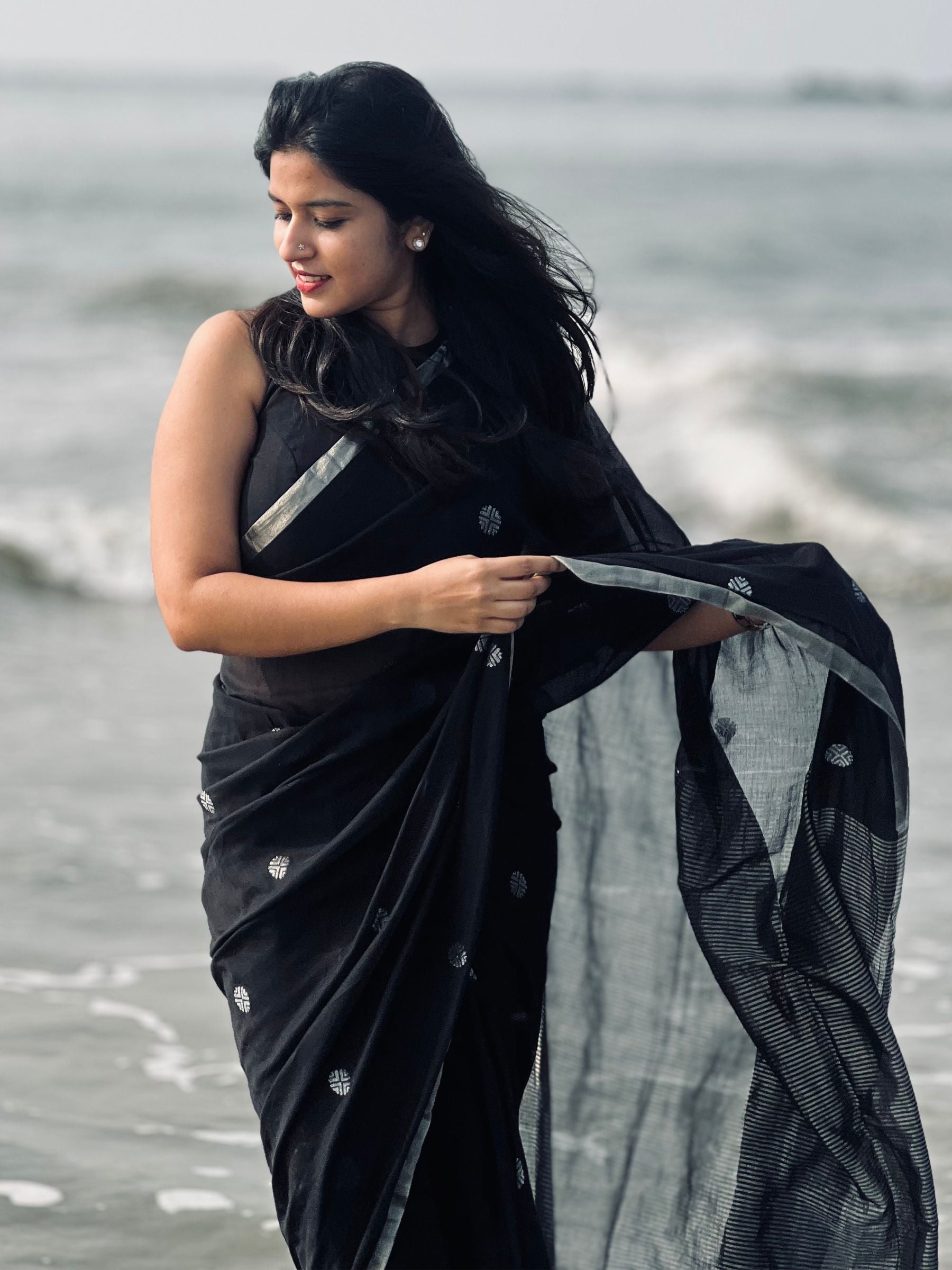 Woman in a black saree with silver details by the water